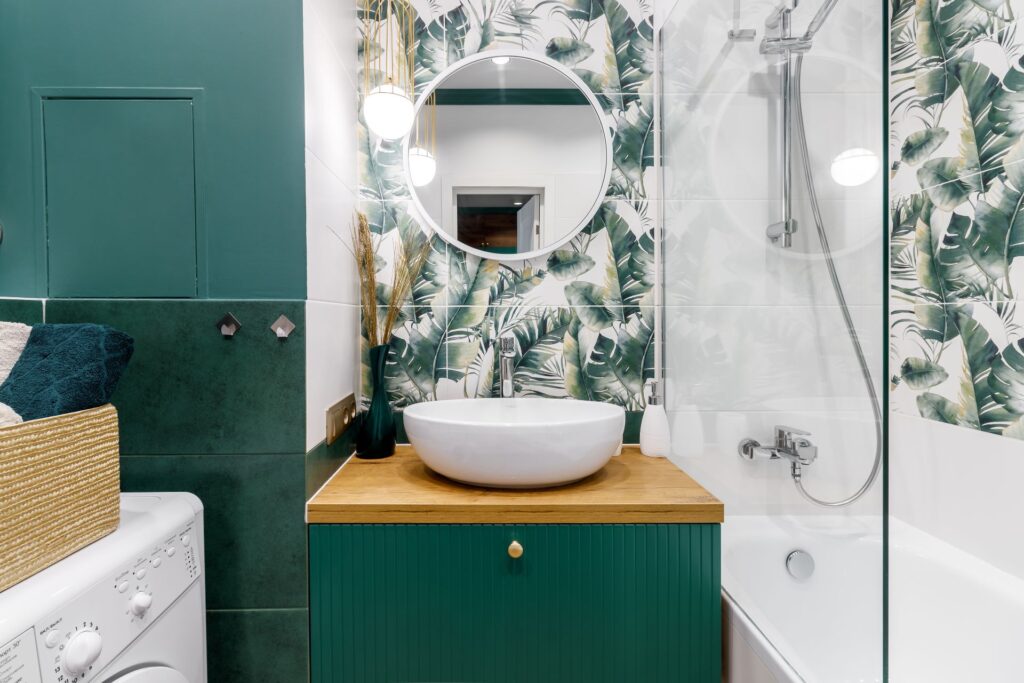 Modernes kleines Badezimmer mit grünen Fliesen, rundem Spiegel, Waschtisch mit Holzoberfläche und Duscharmatur