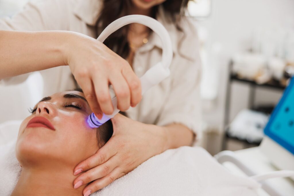 Frau bei Hydrafacial Behandlung in einem modernen Kosmetikstudio – gezielte Gesichtsreinigung mit Licht- und Saugtechnologie
